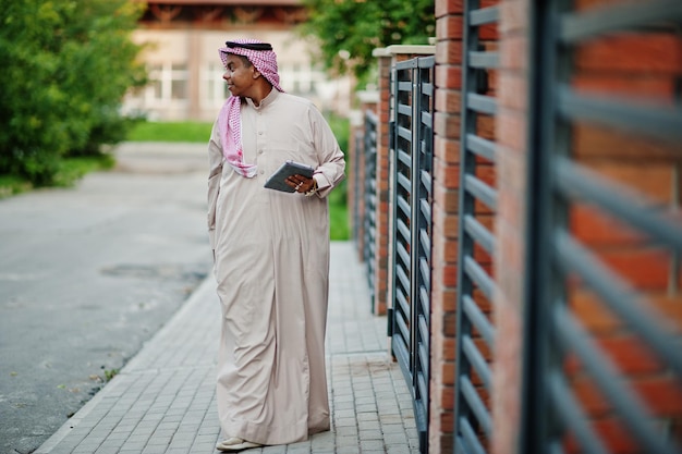 Photo gratuite homme arabe du moyen-orient posé dans la rue contre un bâtiment moderne avec une tablette à portée de main