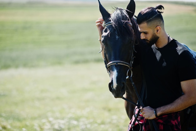 Homme arabe à grande barbe en noir avec cheval arabe