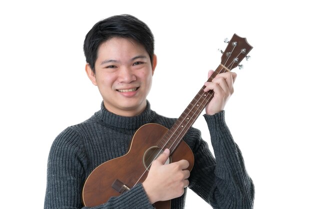 Un homme asiatique amical aime jouer et chanter avec un t-shirt gris ukulélé fond blanc