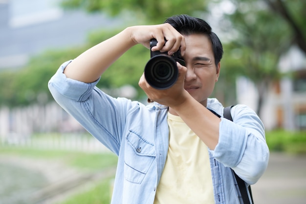 Homme asiatique habillé par hasard prenant des photos dans le parc