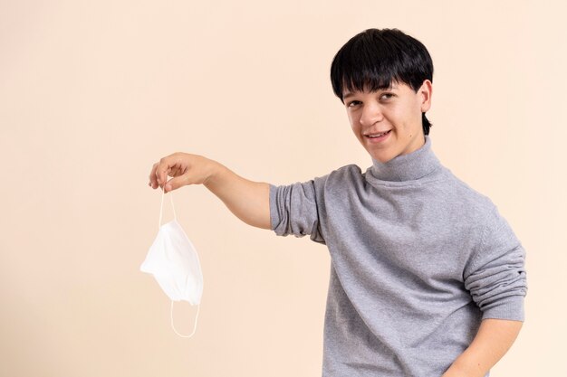 Homme asiatique avec le nanisme tenant un masque médical