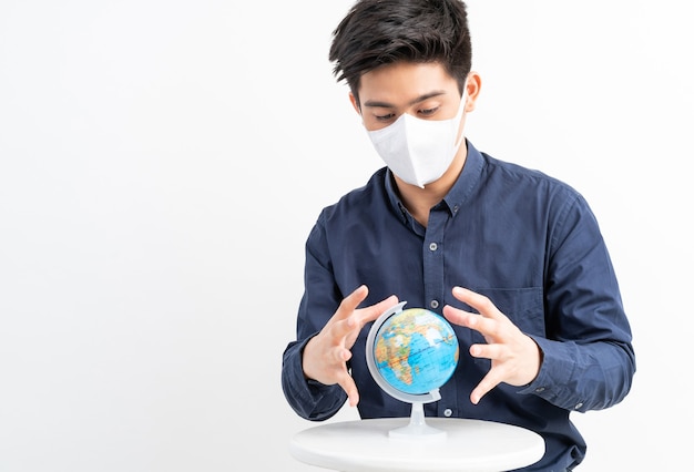 Homme asiatique portant un masque facial tenant la carte de la carte du monde dans la main