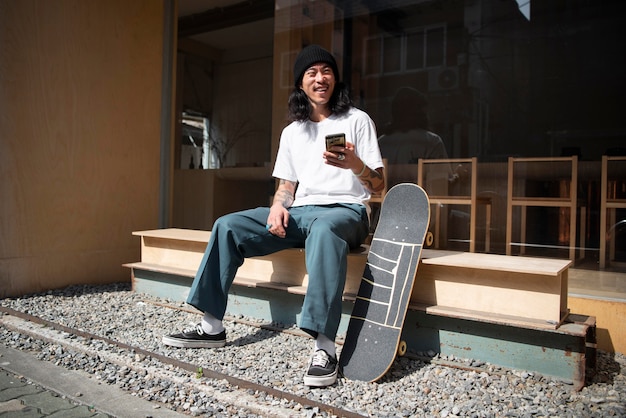 Homme asiatique prenant une pause de la planche à roulettes