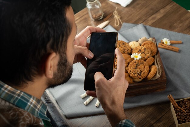 Homme assis autour d'une table à biscuits et jouant avec son téléphone