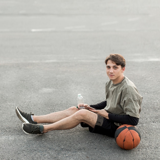 Photo gratuite homme assis avec un ballon de basket