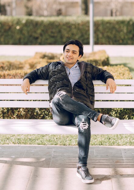 Homme assis sur le banc mettant une jambe sur l'autre. photo de haute qualité