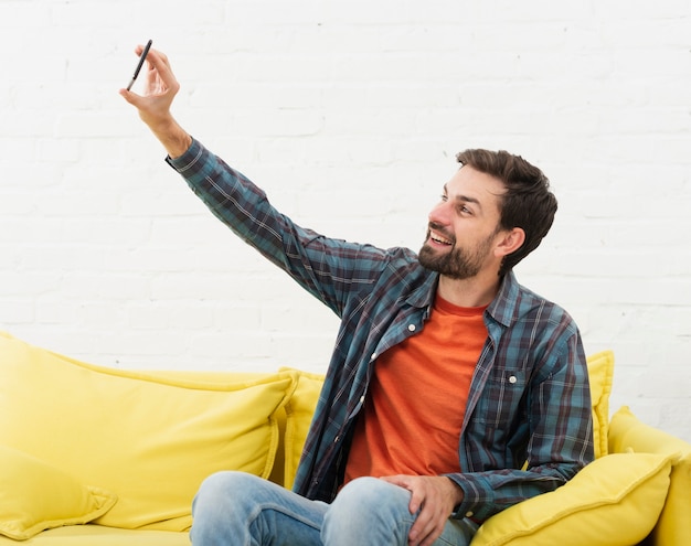 Photo gratuite homme assis sur un canapé et prenant des selfies