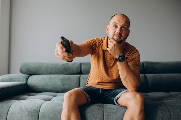 Homme assis sur un canapé avec télécommande