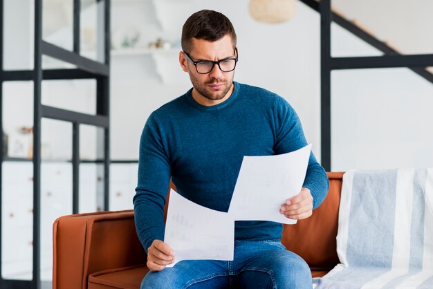 Homme assis sur un cauch et lisant des documents