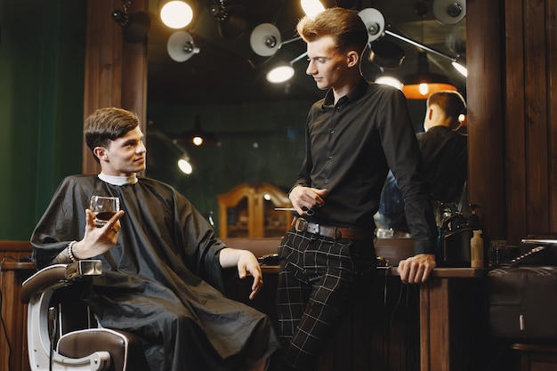 Homme assis sur une chaise. Coiffeur avec un client. Guy boit un whisky.