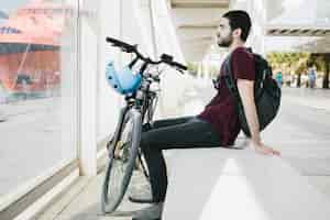 Photo gratuite homme assis à côté d'un vélo