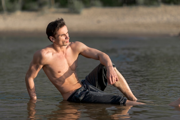 Homme assis dans l&#39;eau à la plage