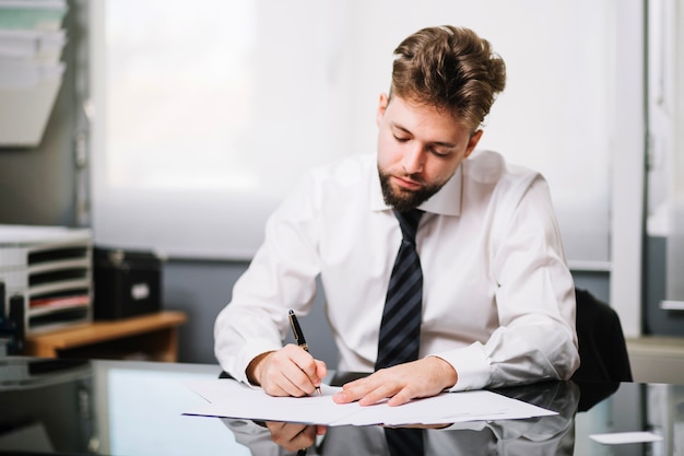 Homme assis et écrit au bureau