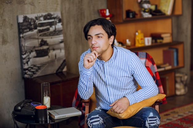 Homme assis sur le fauteuil dans un café et rêvant. photo de haute qualité