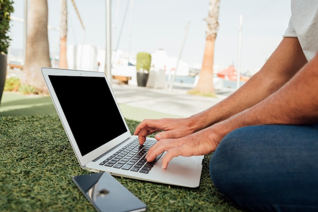 Homme assis sur l'herbe avec des appareils portables