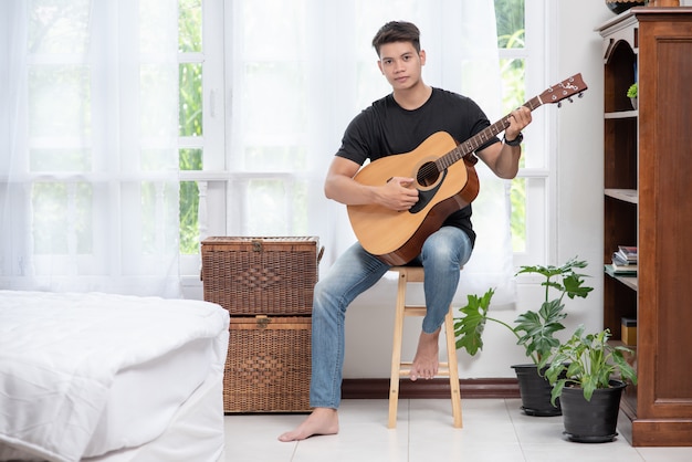 Un homme assis et jouant de la guitare sur une chaise.