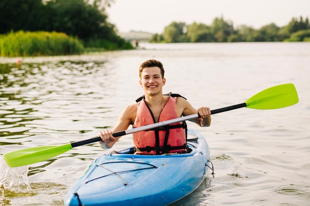 Homme assis en kayak à l&#39;aide de pagaie sur le lac