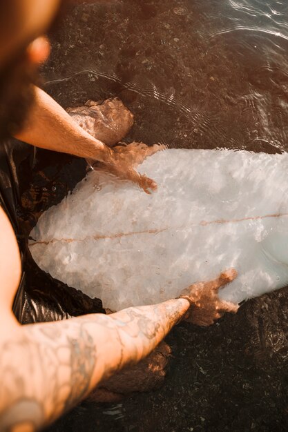 Homme assis sur une planche de surf blanche dans l&#39;eau