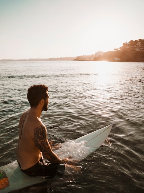Homme assis sur une planche de surf dans l&#39;eau