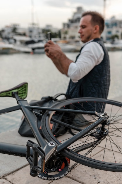 Photo gratuite homme assis un prendre une photo à côté de son vélo