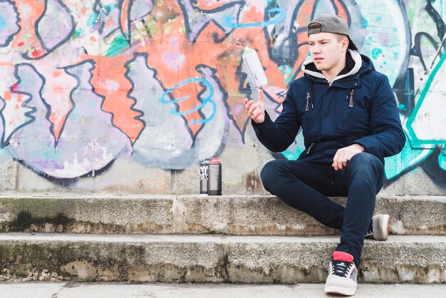 Homme assis près du mur de graffitis