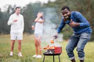 Photo gratuite homme assistant au barbecue et abandonnant les pouces vers le haut