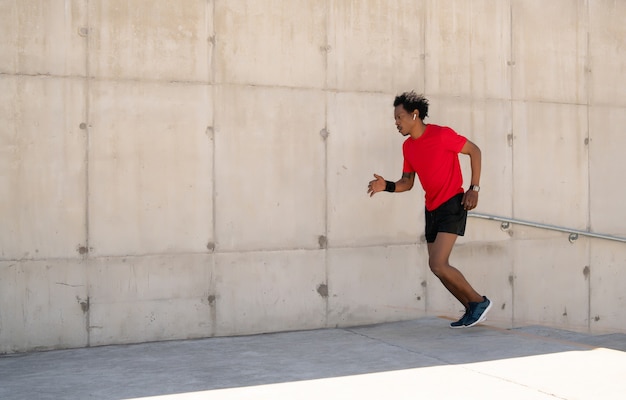 Homme athlétique afro en cours d'exécution et faire de l'exercice à l'extérieur dans la rue