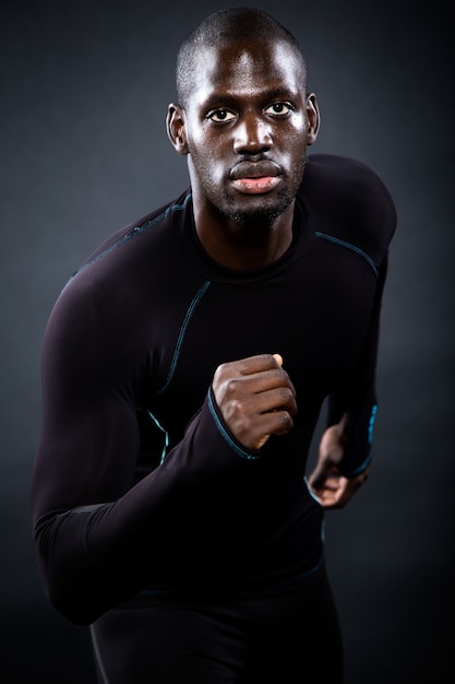 Homme athlétique courir dans un fond noir.