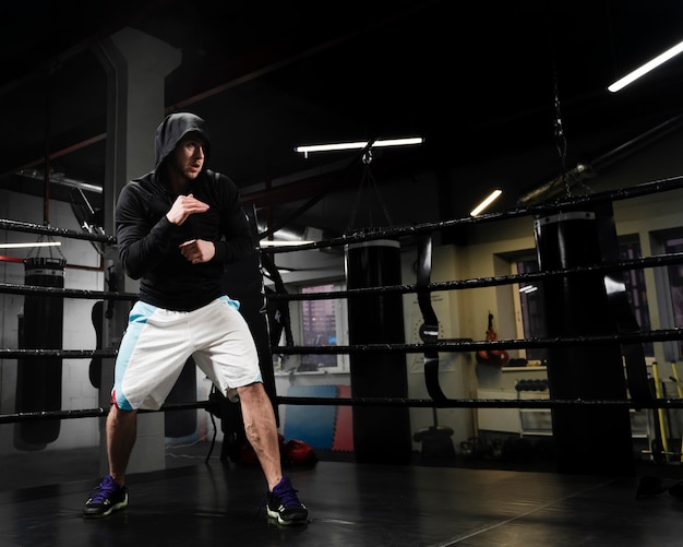 Homme athlétique à long tir de formation en ring de boxe