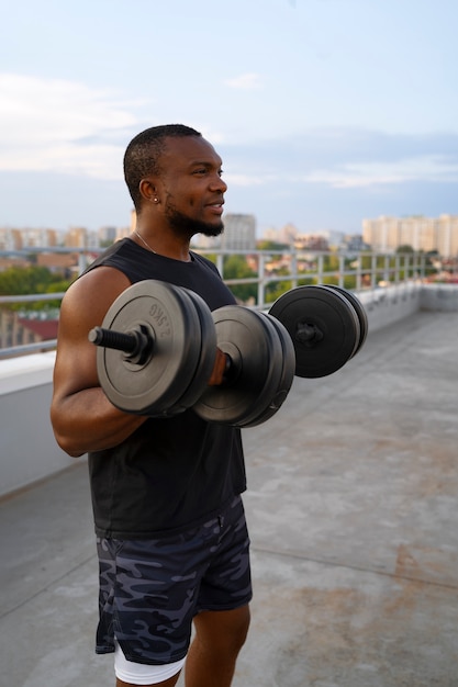 Photo gratuite homme athlétique s'entraînant à l'extérieur avec des poids