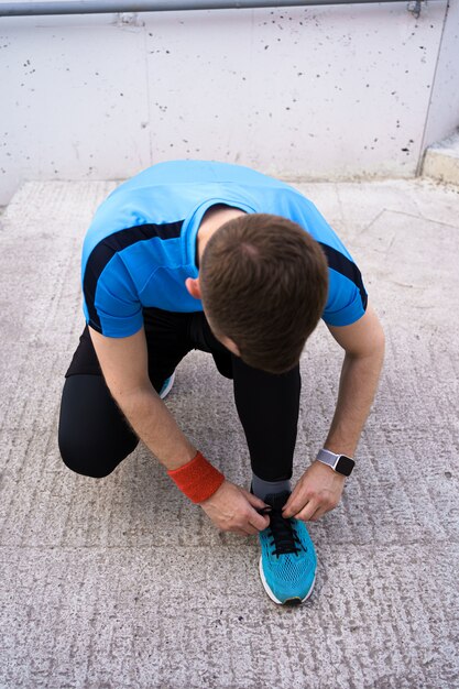 Homme attachant ses chaussures de sport sur fond de béton