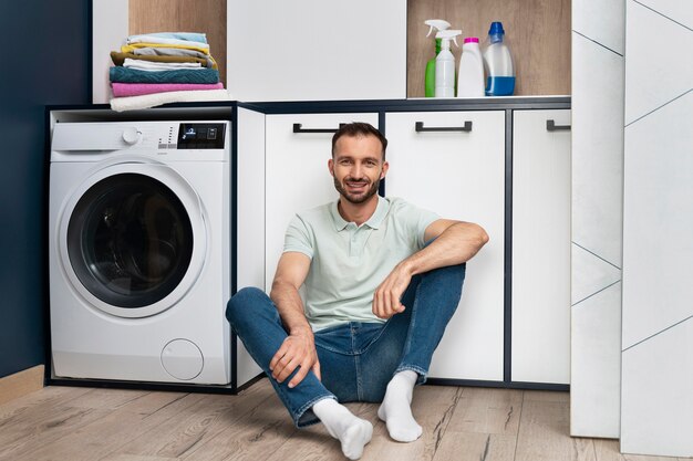 Homme attendant que la machine à laver termine son programme