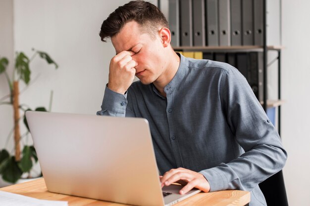 Homme au bureau pendant une pandémie souffrant de maux de tête