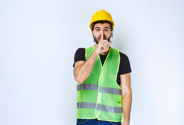 Homme au casque jaune demandant le silence.