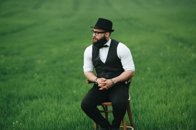 Homme au chapeau assis sur une chaise à l&#39;extérieur