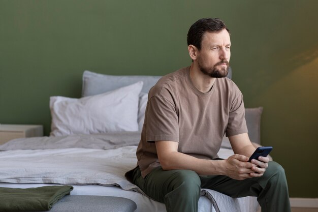Homme au lit avec smartphone