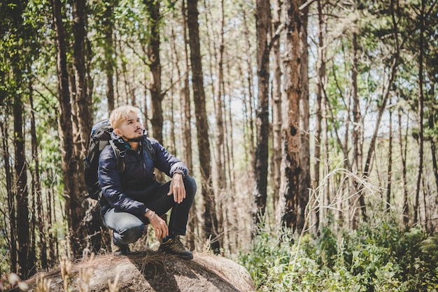 Homme au sommet de la montagne assis sur le rocher regardant une belle nature autour. Concept de style de vie masculin.