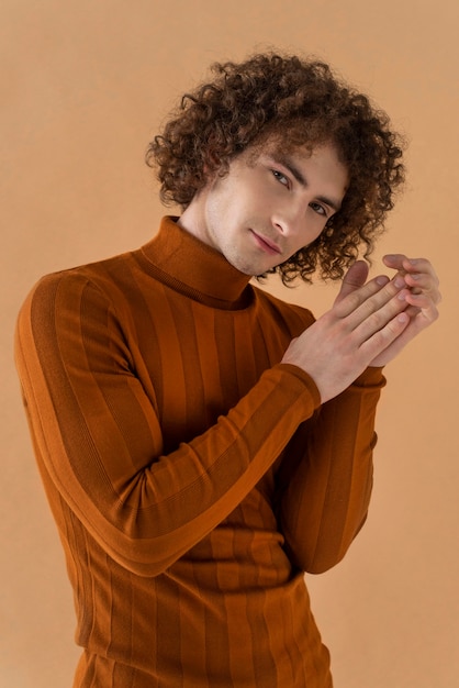 Homme aux cheveux bouclés avec chemisier marron posant