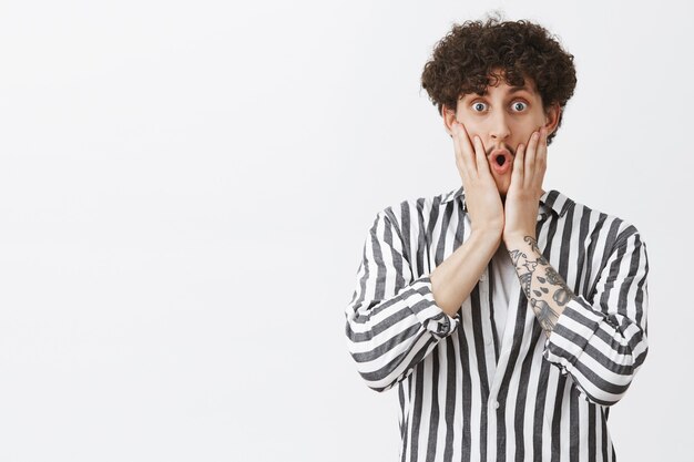 Homme aux cheveux bouclés surpris et étonné qui dit wow, l'air étonné