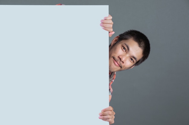 Photo gratuite un homme aux cheveux courts, vêtu d'une chemise à carreaux rouge, porte une étiquette blanche sur un gris.