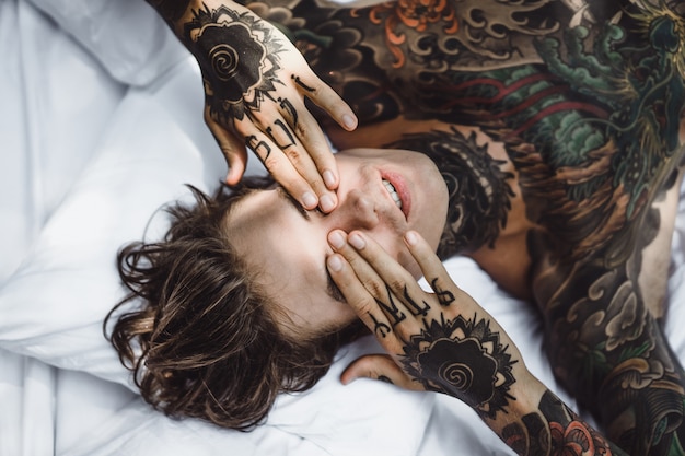 Photo gratuite homme aux tatouages ​​colorés reposant sur une feuille blanche