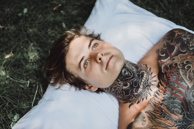 Photo gratuite homme aux tatouages ​​colorés reposant sur l'herbe