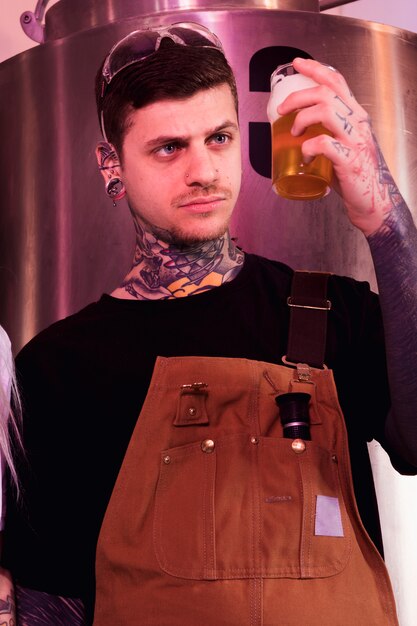 Homme aux tatouages produisant de la bière artisanale