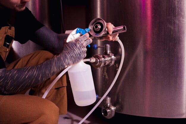 Homme aux tatouages produisant de la bière artisanale