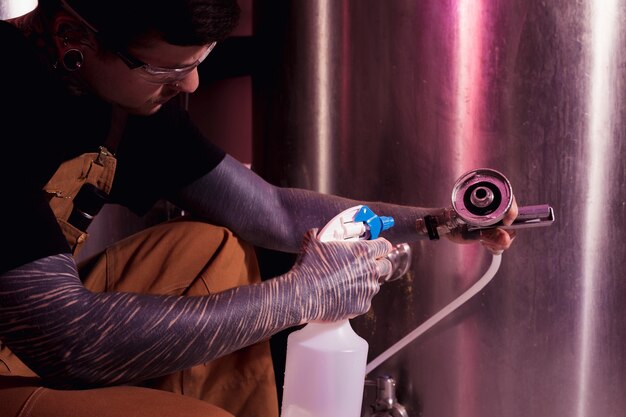 Homme aux tatouages produisant de la bière artisanale