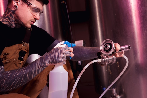 Homme aux tatouages produisant de la bière artisanale
