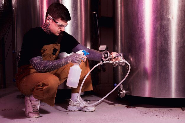 Homme aux tatouages produisant de la bière artisanale