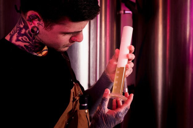 Homme aux tatouages produisant de la bière artisanale