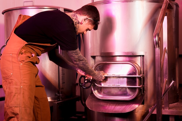 Photo gratuite homme aux tatouages produisant de la bière artisanale