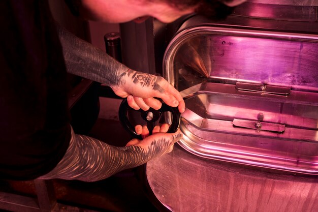 Homme aux tatouages produisant de la bière artisanale